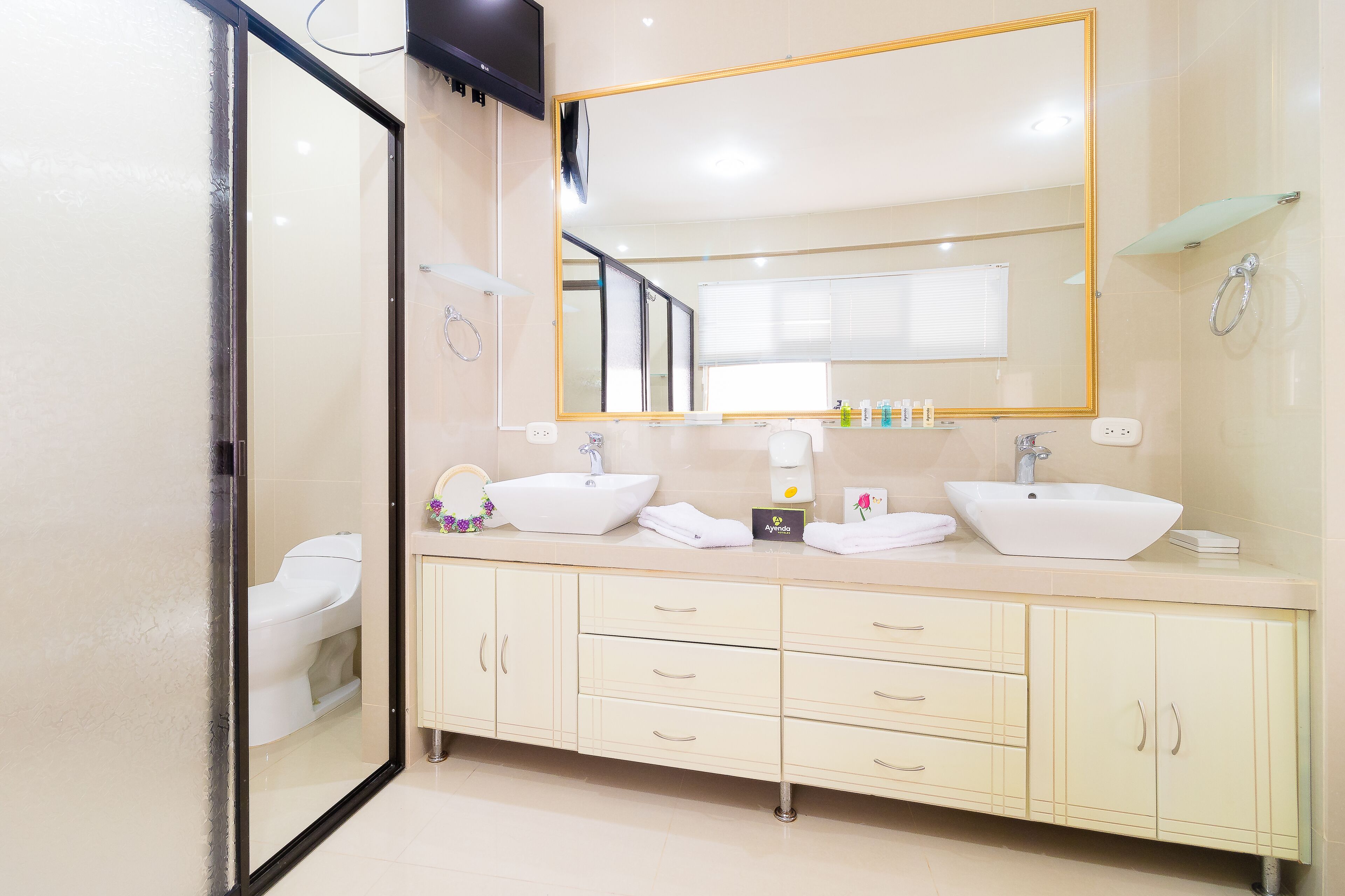 A modern bathroom with two sinks, a large mirror, and a toilet.
