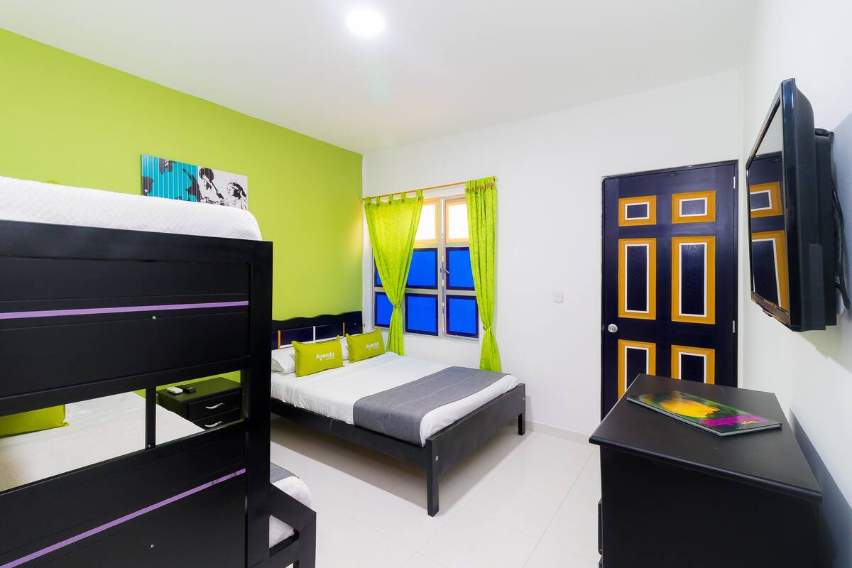 Una habitación con cama, escritorio, ventana con cortinas y puerta.