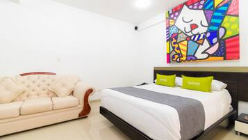 Relax in a stylish space with a large bed, tufted sofa, and vibrant artwork.