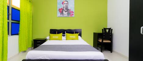 A hotel room with a bed, two nightstands, a chair, a green wall, and a poster.