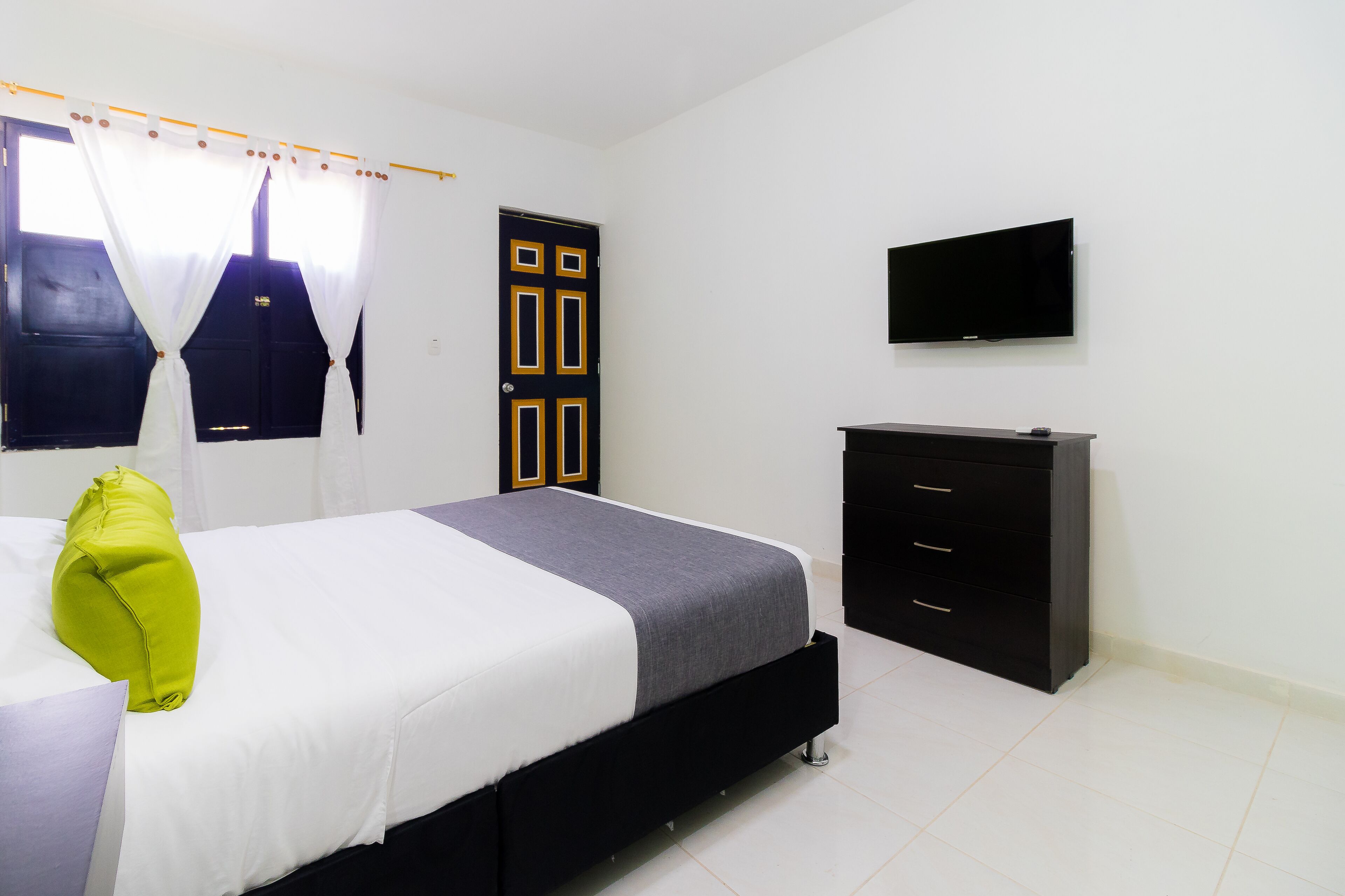 A bedroom with a bed, a television, a wardrobe, and a door with a unique design.