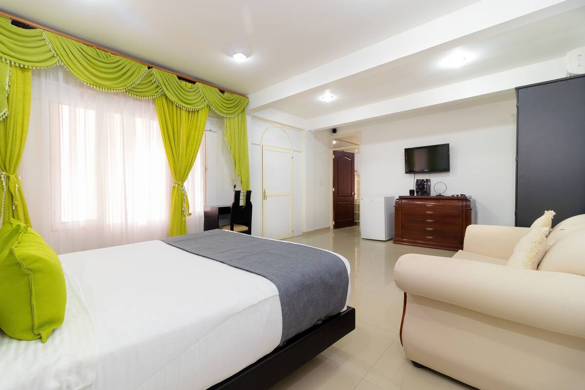 Una habitación de hotel con cama, sofá, televisión y armario.