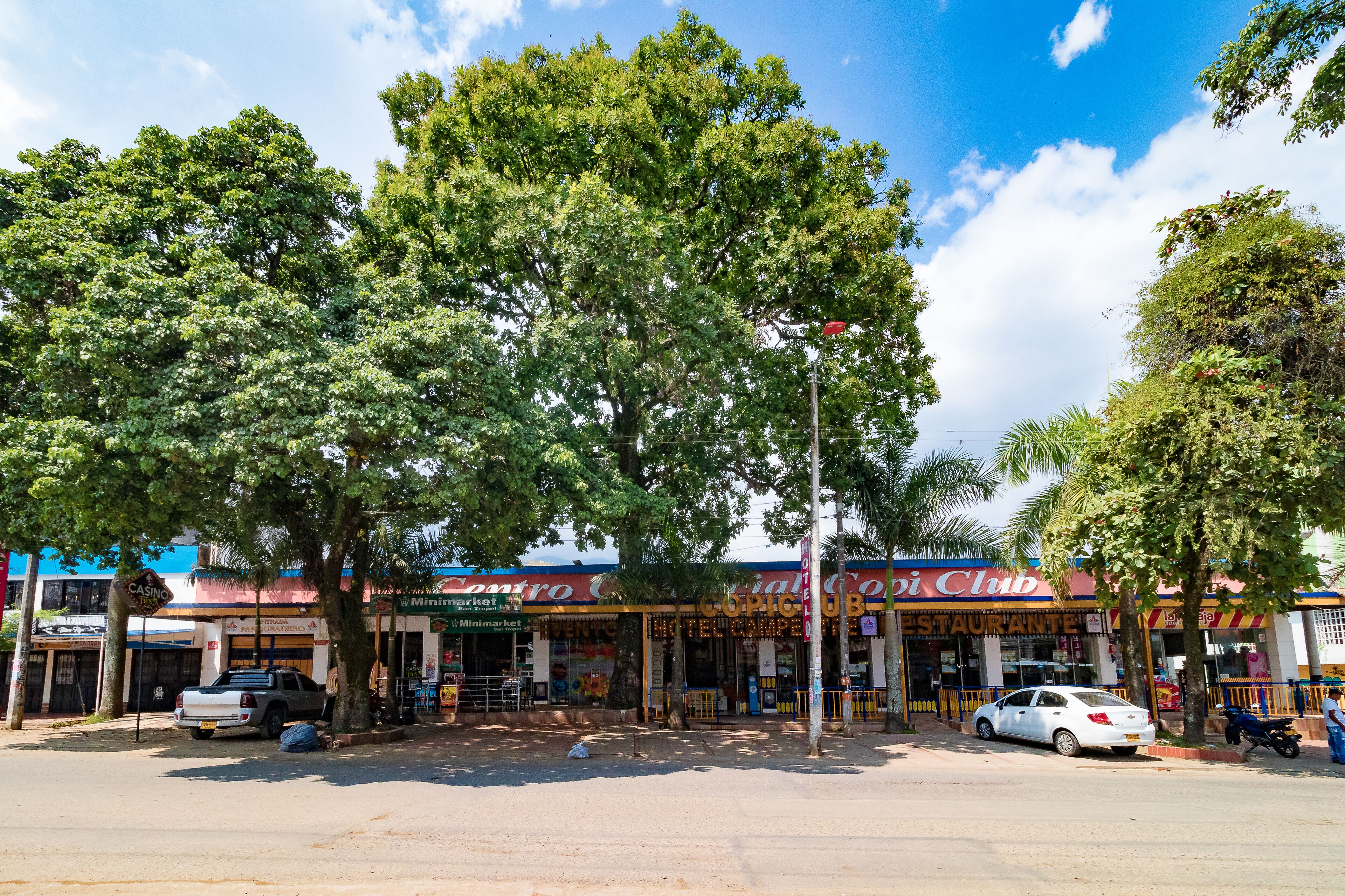 Vista de una calle con una hilera de tiendas, incluyendo un casino, un mercado y un club.