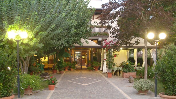 Un patio con suelo de piedra, plantas en macetas y mobiliario exterior.