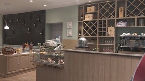 Un restaurante con zona de bar, botellas de vino en la pared y una máquina de café.