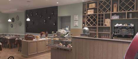 A restaurant with a bar area, wine bottles on the wall, and a coffee machine.