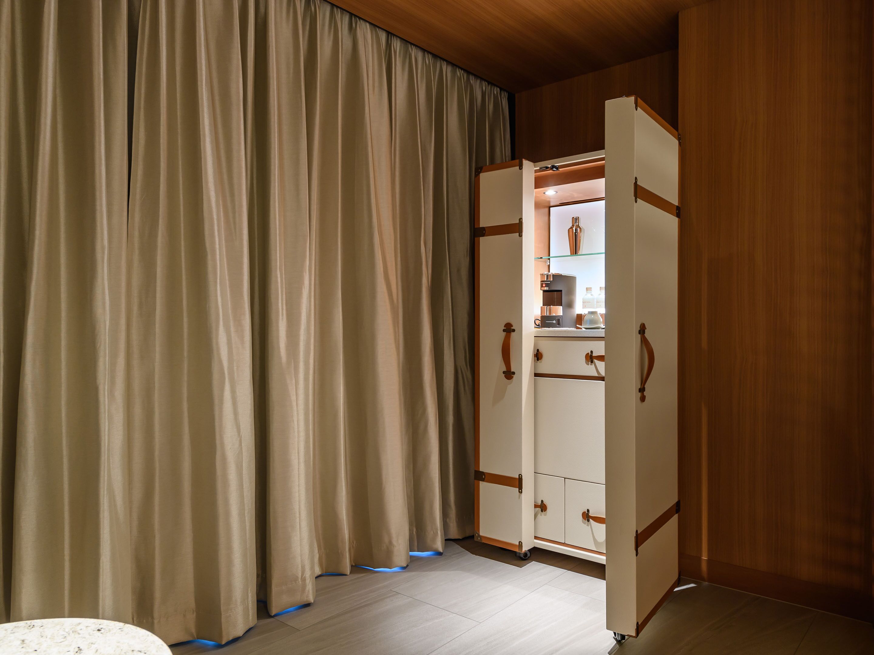 Una habitación con armario, cortina y una pequeña mesa.