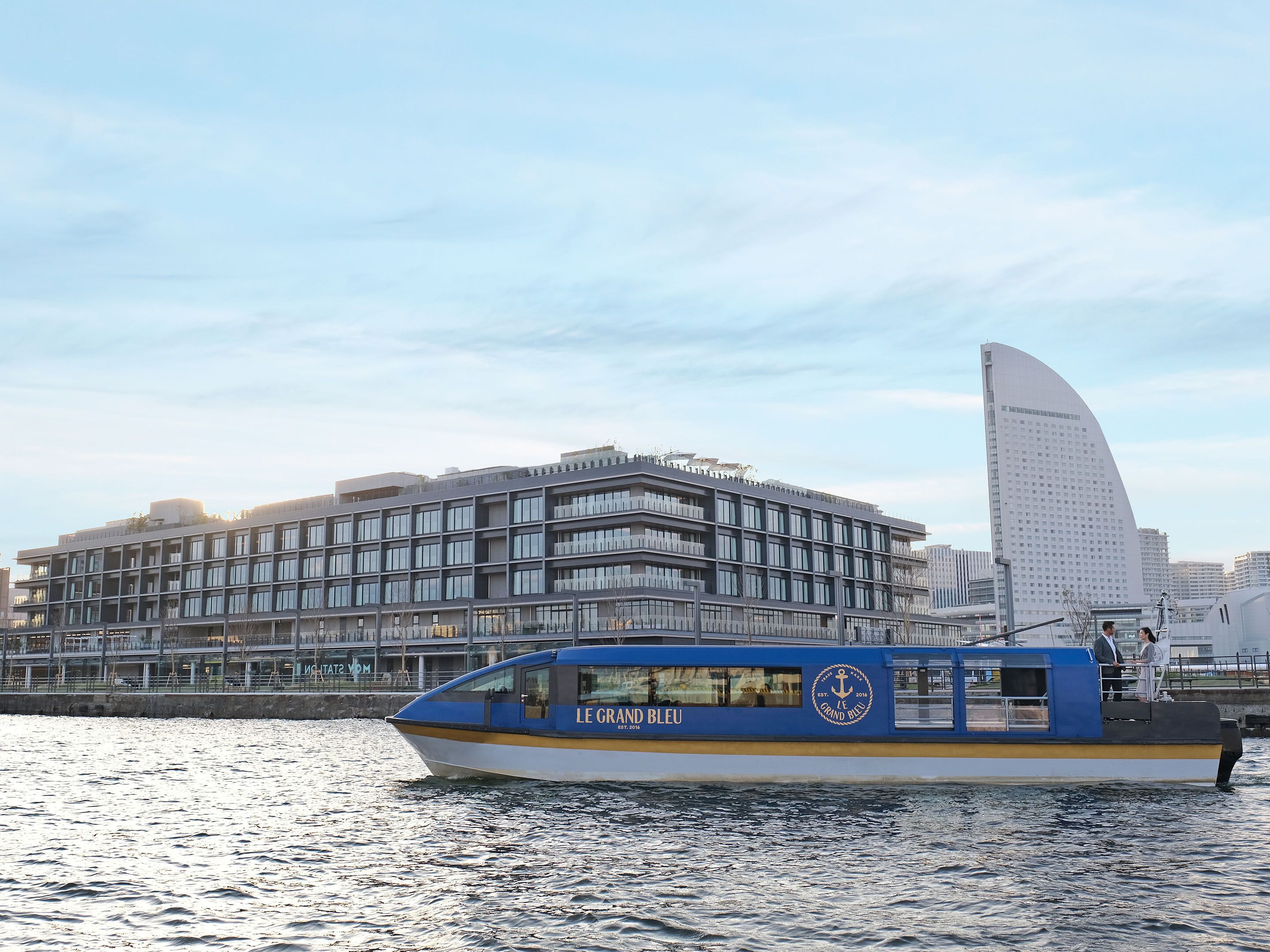 A modern building with a curved facade and a boat docked in front.