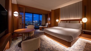 Une chambre d’hôtel avec un grand lit, un bureau, une chaise, une télévision et une vue sur la ville.