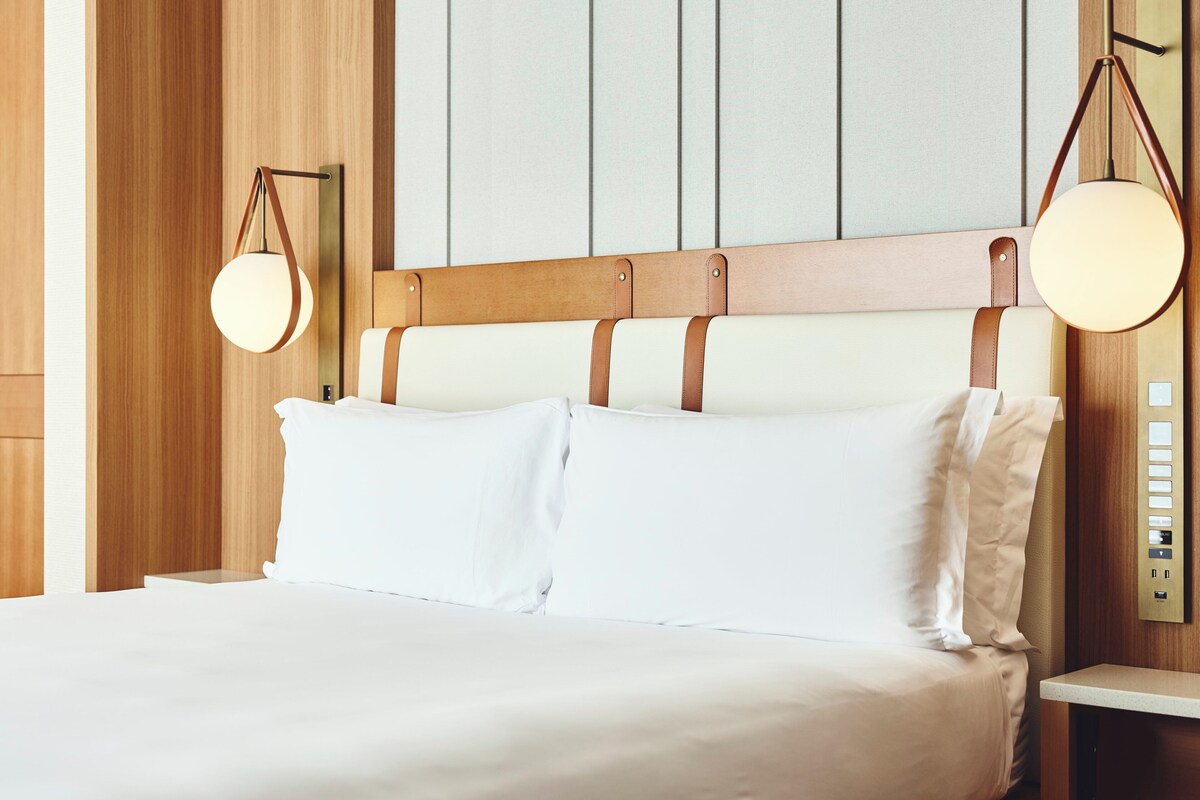 A neatly made bed with a wooden headboard and two bedside lamps.