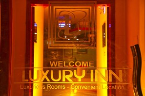 A sign for the Luxury Inn with a welcoming message and a logo.