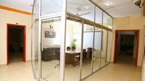 A conference room with glass walls, a ceiling fan, and a whiteboard. - Luxury Inn (Karachi)