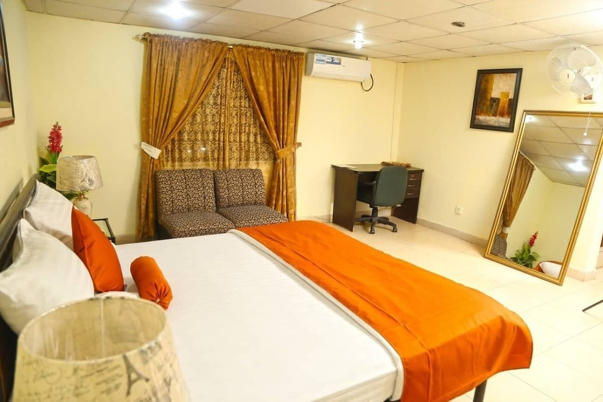 Ein Hotelzimmer mit einem großen Bett, einem Schreibtisch, einem Stuhl und einem Spiegel.