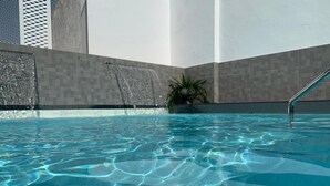 A clear indoor swimming pool with a visible water feature and a palm plant. - Soho Boutique Sevilla (Seville)