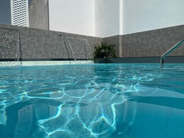 Una piscina al aire libre de temporada, sombrillas