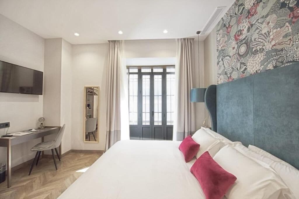 Una habitación de hotel moderna con una cama grande, un escritorio y un televisor.