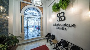 A boutique hotel entrance with a wrought iron gate, seating area, and a wall-mounted sign for 'sohoBoutique Sevilla'. - Soho Boutique Sevilla (Seville)