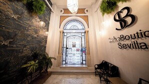 A lobby with a stone wall, a glass door, and a sign reading "SchoBoutique Sevilla". - Soho Boutique Sevilla (Seville)