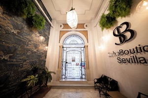 Un vestíbulo con pared de piedra, puerta de cristal y un letrero que dice "SchoBoutique Sevilla".