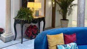 A lobby with a blue sofa, a mirror, a lamp, and a potted plant. - Soho Boutique Sevilla (Seville)