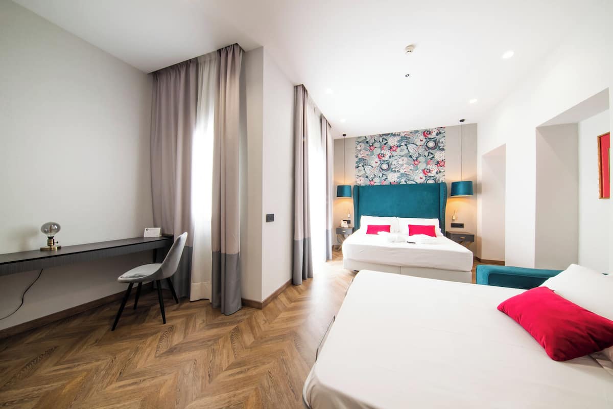 A hotel room with a bed, a desk, a chair, and a nightstand.