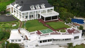 A large, white, multi-story building with a spacious lawn, a tennis court, and a swimming pool. - Fogo Resort (San Antonio)