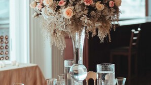 A table set with clear glassware and a large floral centerpiece. - Fogo Resort (San Antonio)