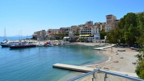 A coastal town with a marina, sandy beach, and buildings along the waterfront. - Hotel Titania (Sarandë)