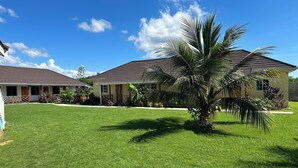 A two-story house with a well-maintained lawn and a palm tree. - Yoga Dreams Negril (Negril)