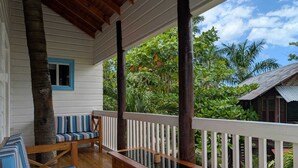 A wooden deck with a bench and striped cushions, surrounded by lush greenery and a clear sky. - Yoga Dreams Negril (Negril)