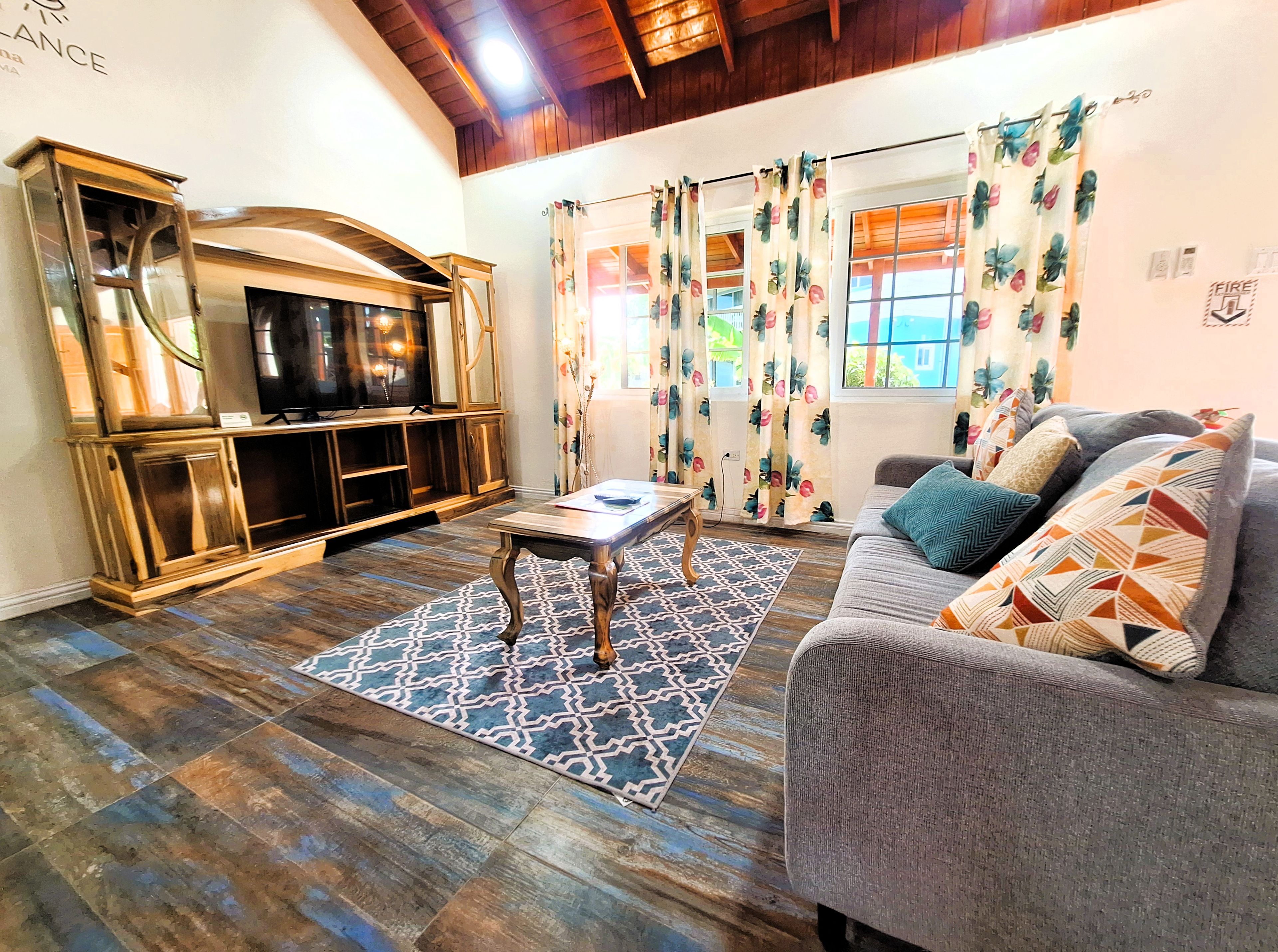 Un soggiorno con un mobile TV in legno, un divano con cuscini decorati e un tappeto fantasia.