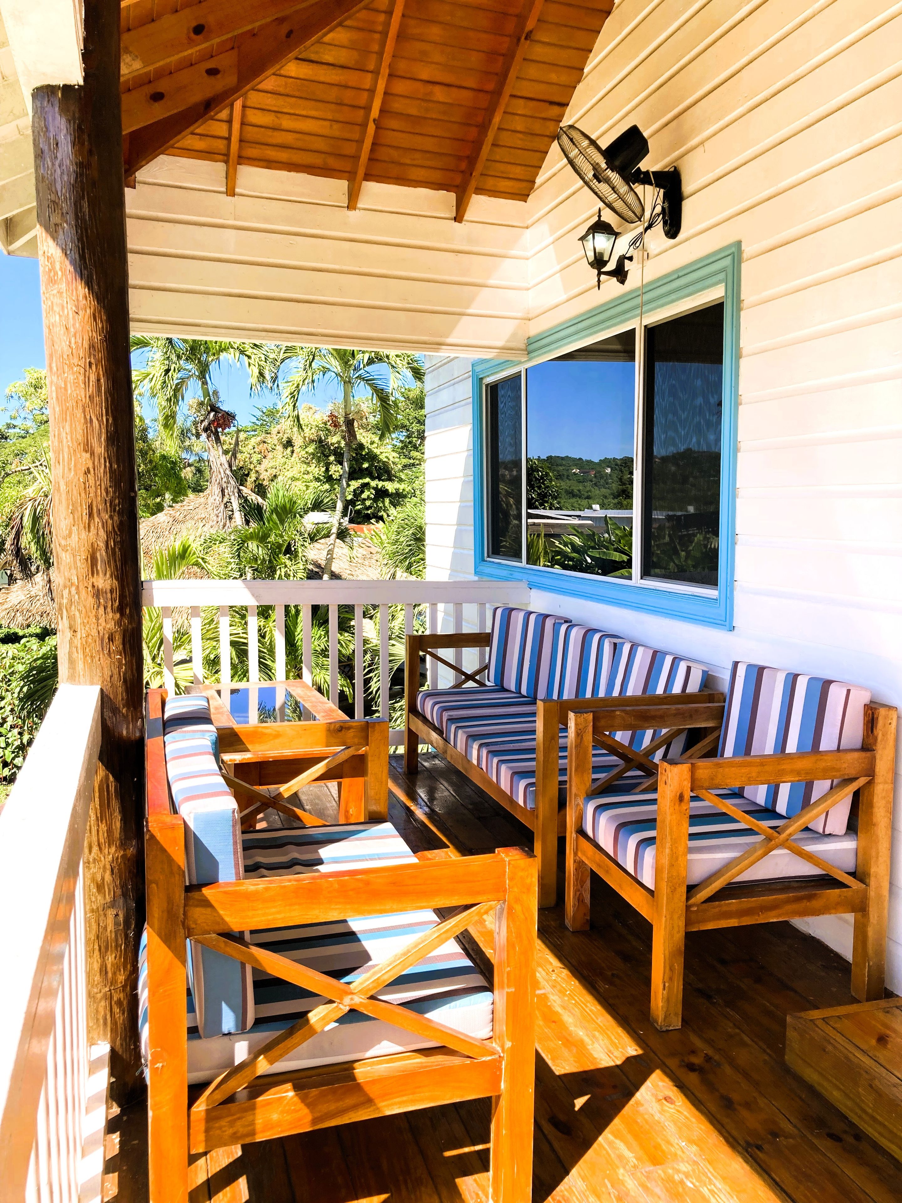 A covered outdoor seating area with wooden furniture and a view of the surrounding landscape.