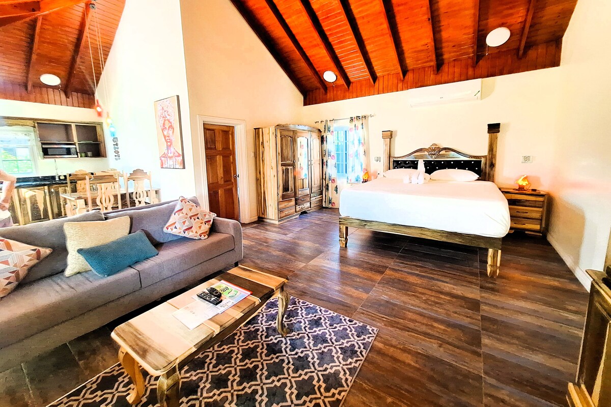 A spacious room with a large bed, a sofa, a wooden coffee table, and a patterned rug.
