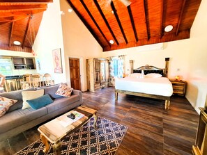 A spacious room with a large bed, a sofa, a wooden coffee table, and a patterned rug. - Yoga Dreams Negril (Negril)