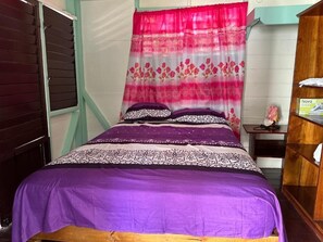 A bed with a purple bedspread and a pink floral curtain. - Yoga Dreams Negril (Negril)
