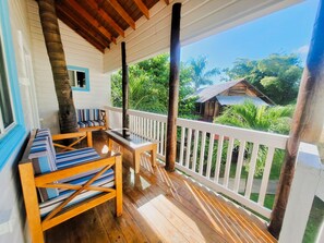A wooden deck with a white railing, a bench, and a table. - Yoga Dreams Negril (Negril)