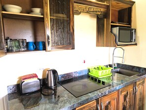 A kitchen with a microwave, a kettle, a toaster, and a green dish rack. - Yoga Dreams Negril (Negril)