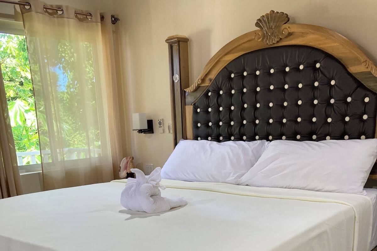 A neatly made bed with white linens, a wooden headboard with a tufted design, and a white towel placed on the bed.
