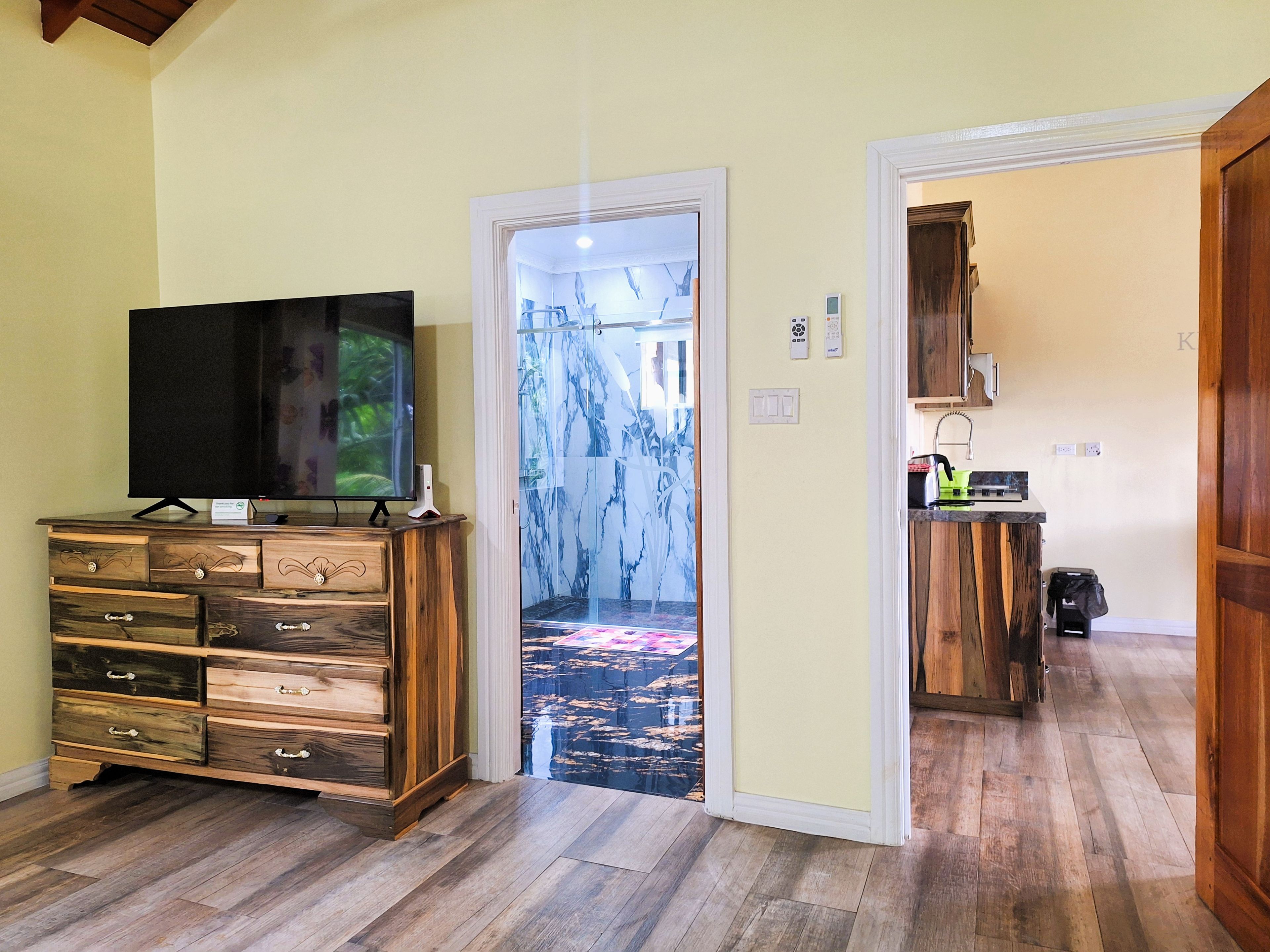 Una habitación con un aparador de madera, un televisor de pantalla plana y una puerta que da a un pasillo con una alfombra estampada.