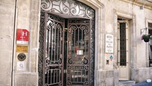 Entrada de un hotel con puertas metálicas ornamentadas, un letrero que indica que es un hotel de 4 estrellas y una placa con una clasificación de estrellas.