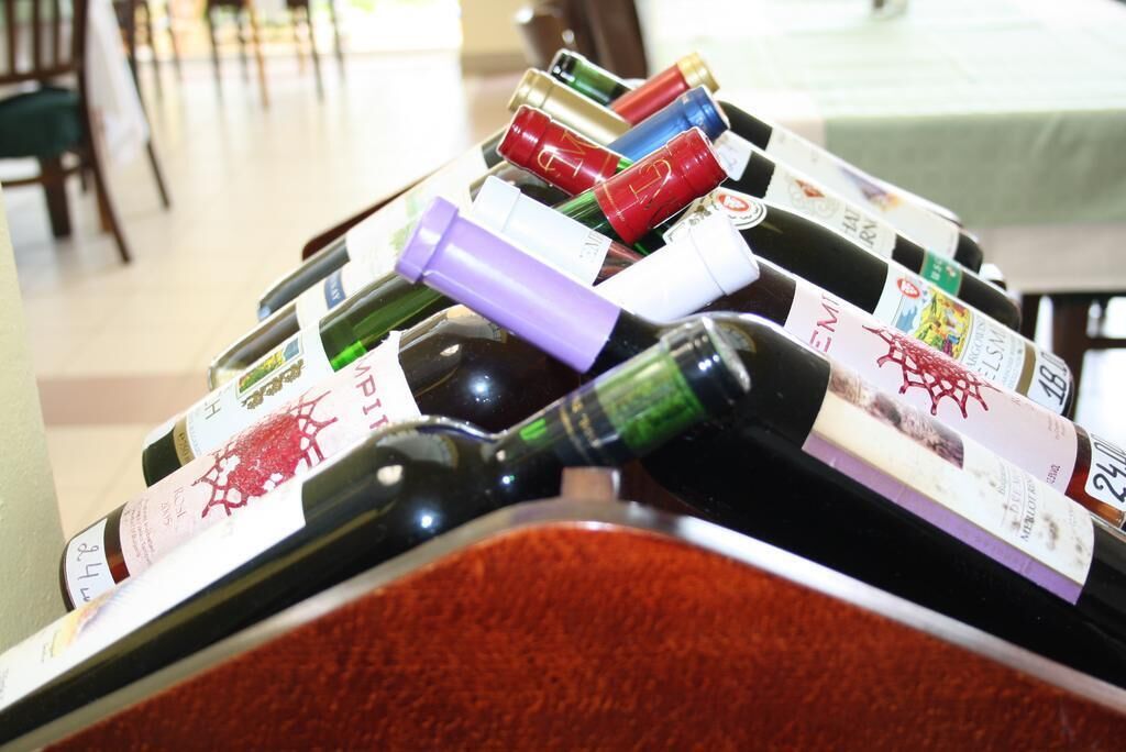 A collection of wine bottles with labels, some with caps removed, on a table.