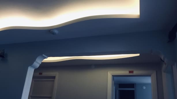 A hallway with a modern ceiling design, two doors labeled '204' and '203', and a white pipe running along the wall. - Hotel Dinlen (Izmir)