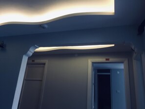A hallway with a modern ceiling design, two doors labeled '204' and '203', and a white pipe running along the wall. - Hotel Dinlen (Izmir)