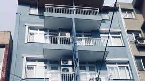 A multi-story building with balconies, air conditioning units, and a digital display board. - Hotel Dinlen (Izmir)