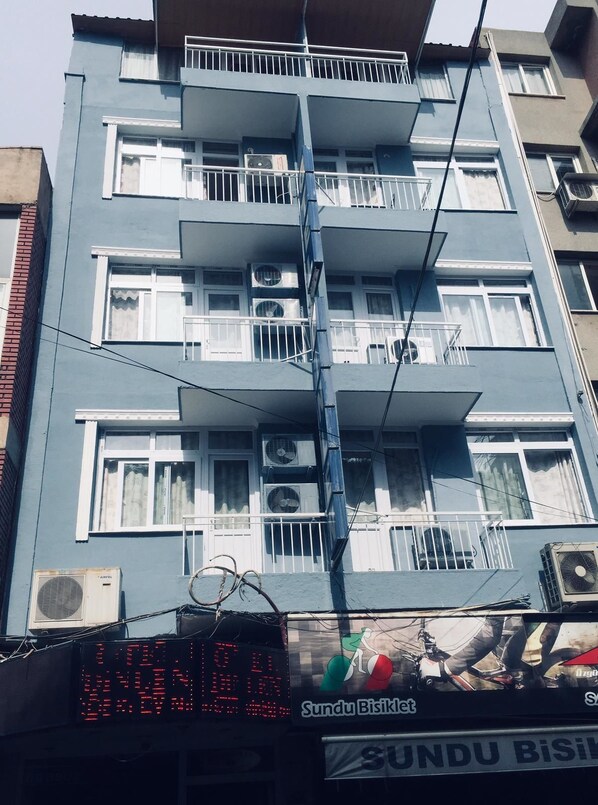 A multi-story building with balconies, air conditioning units, and a digital display board. - Hotel Dinlen (Izmir)