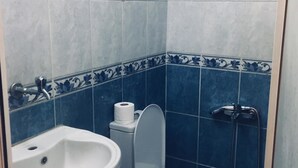 A small bathroom with a toilet, sink, and shower. - Hotel Dinlen (Izmir)