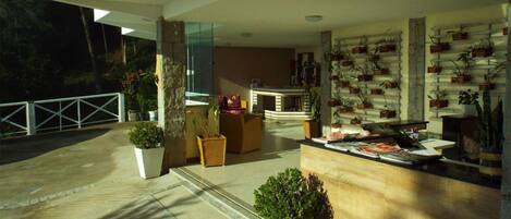 A modern lobby with a reception desk, seating area, and potted plants.