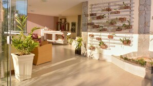 Un vestíbul modern amb una taquilla d'adreça, plantes en testos i una paret decorada amb plantes.