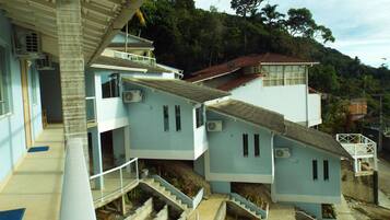 Un edificio de varios pisos con una escalera que lleva a un balcón, rodeado de follaje y árboles.