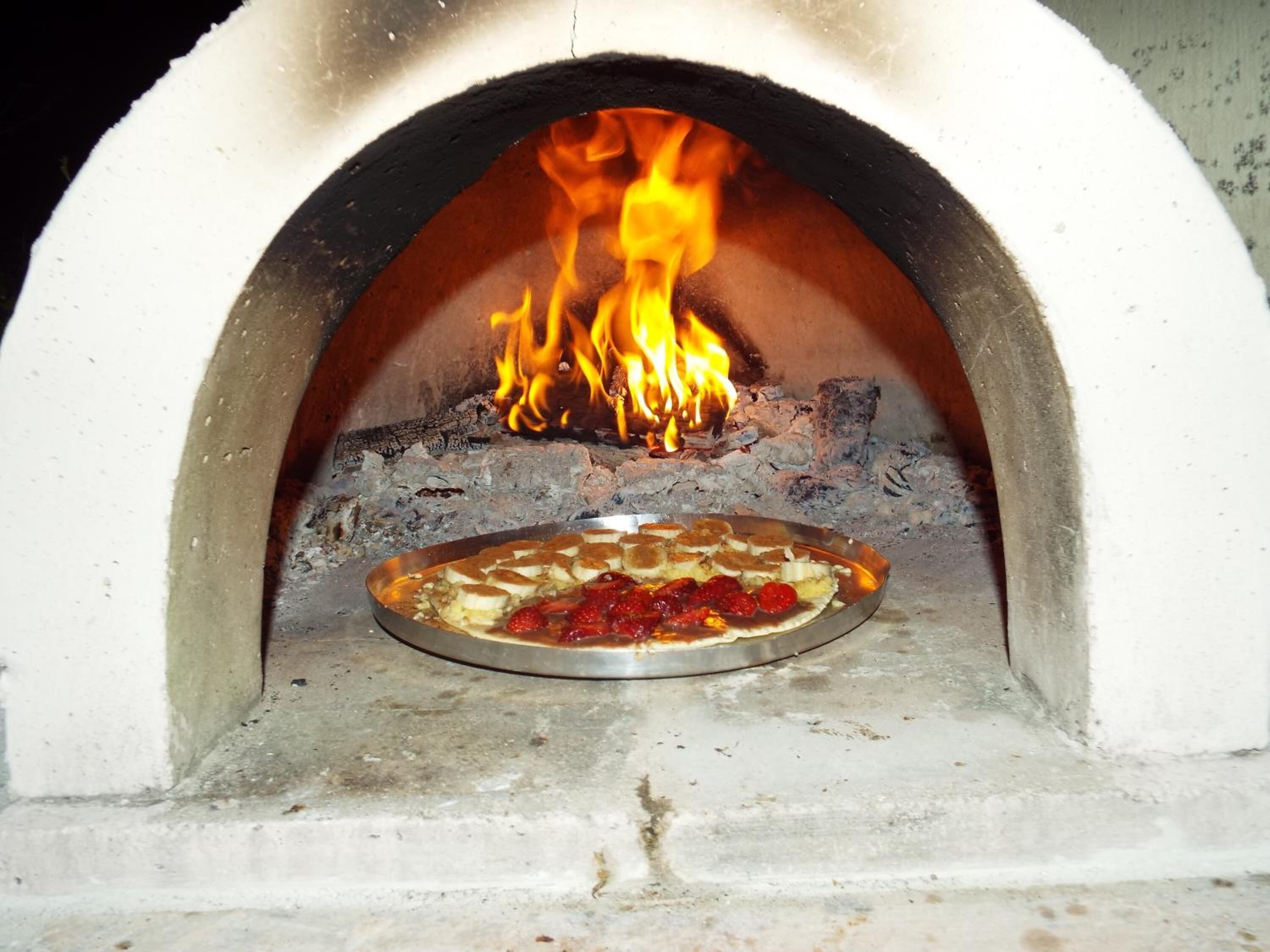 Een pizzaoven met een pizza erin, vlammen branden erboven.